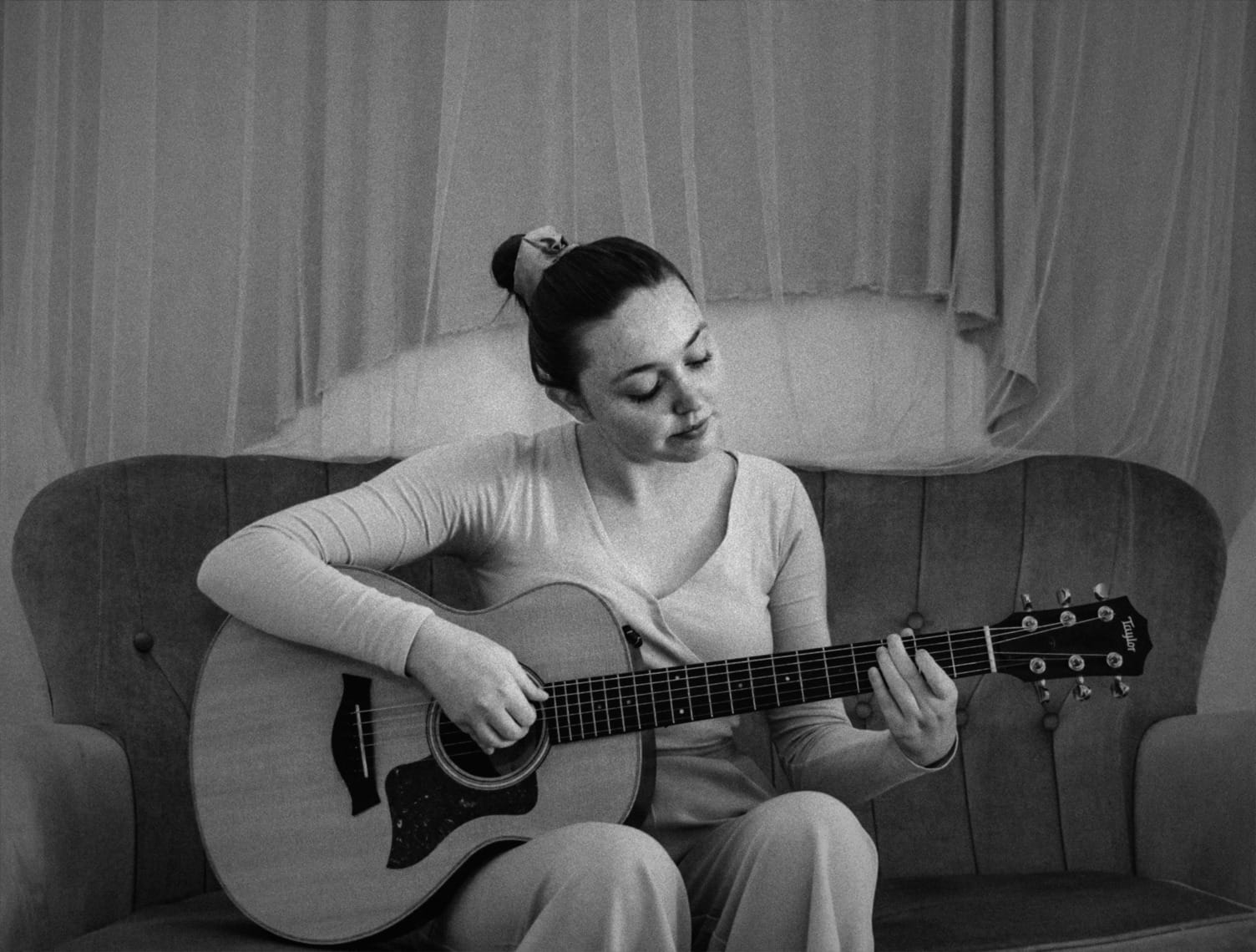 woman in white long sleeve shirt playing acoustic guitar