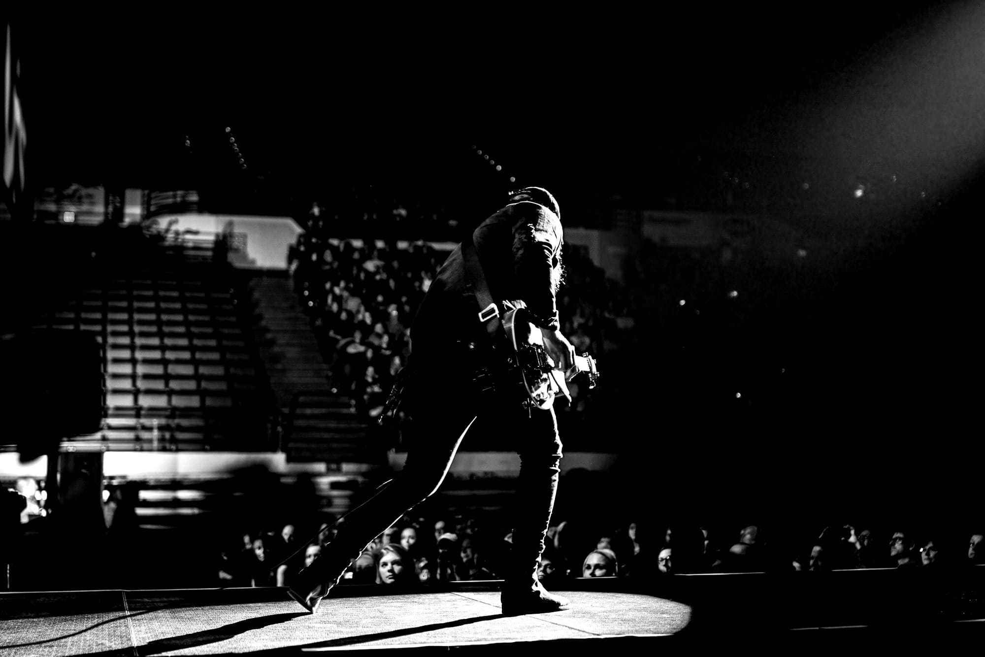 man in black jacket and black pants playing guitar on stage